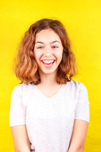 Portrait of smiling young woman against yellow background