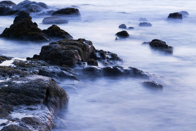 Scenic view of rocks in sea against sky