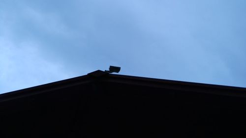 Low angle view of silhouette houses against blue sky