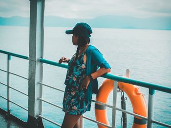 Full length of man standing on railing against sea