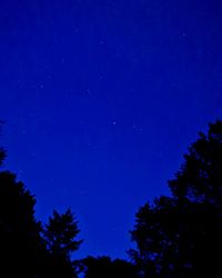 Low angle view of silhouette trees against clear blue sky