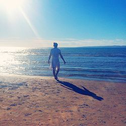Full length of man on beach against sky during sunset