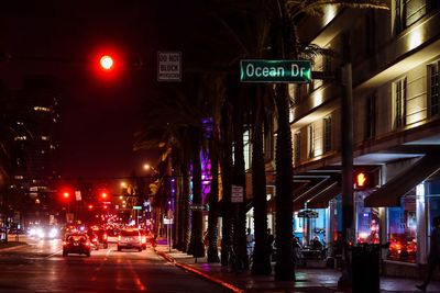 Illuminated road amidst city at night