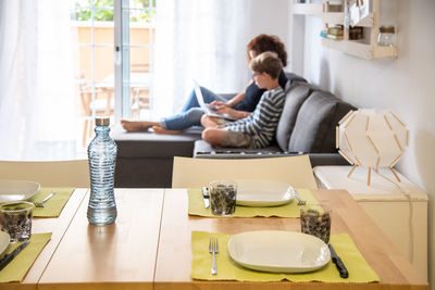 Mother with son using laptop while sitting on sofa at home