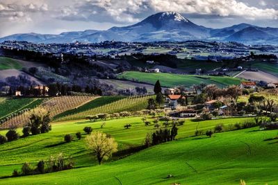 Scenic view of green landscape and mountains against sky