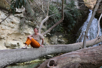 Smiling woman sitting on tree trunk