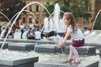 Full length of girl standing by fountain in city