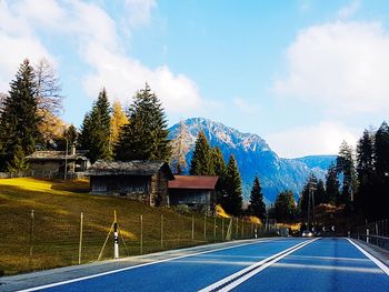 Road by trees against sky during winter