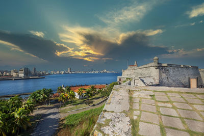 Buildings by sea against sky during sunset