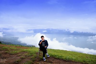 Full length of man on chair on hill against sky