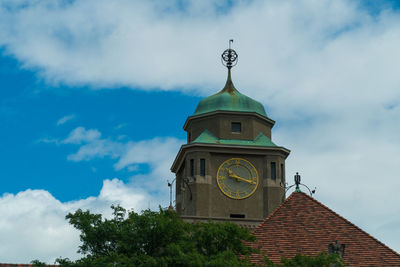 Low angle view of clock tower by building against sky