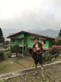 Full length portrait of young man standing against sky