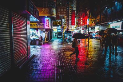Woman walking on wet street in city at night