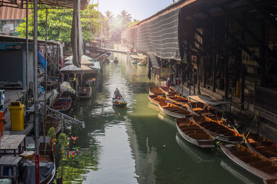 Boats moored in canal amidst buildings