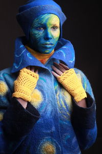 Close-up of young woman with painted face against black background