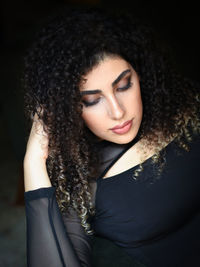 Portrait of young woman looking away against black background