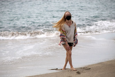 Woman wearing mask walking at beach