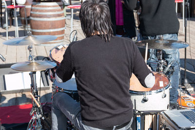 Rear view of man playing music outdoors