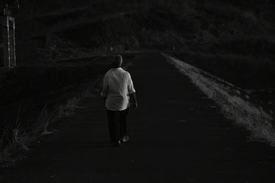 Rear view of woman walking on road at night