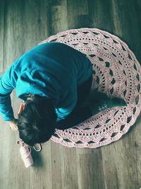 High angle view of boy kneeling on wooden floor