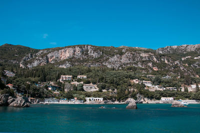 Scenic view of sea and mountains against clear blue sky