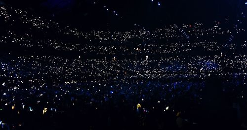 Crowd at music concert against sky at night