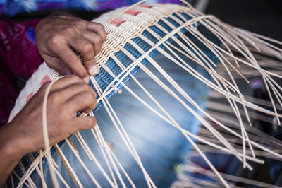 Cropped image of person weaving wicker basket