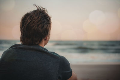 Rear view of boy looking at sea against sky