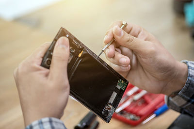 Close-up of man repairing mobile phone