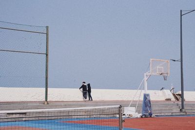 Men standing on wall against clear sky