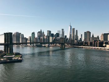 Brooklyn bridge and east river against sky in city