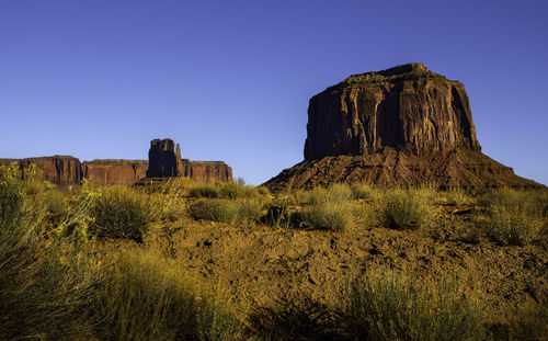 Rock formations on landscape against clear blue sky