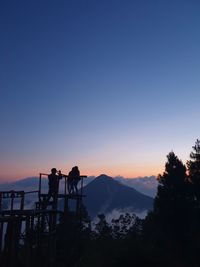 Silhouette people standing on mountain against sky during sunset
