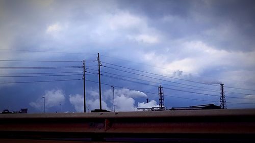 Low angle view of silhouette electricity pylon against sky