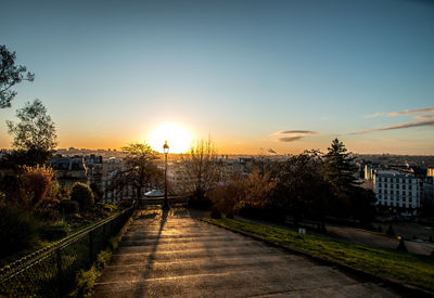 Footpath amidst buildings against sky during sunset