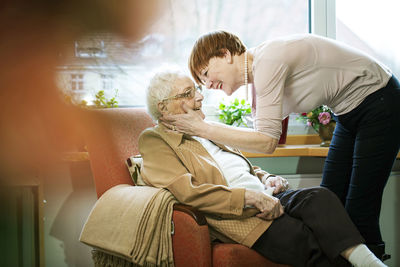 Adult daughter greeting her mother with alzheimer's disease in her room at retirement home