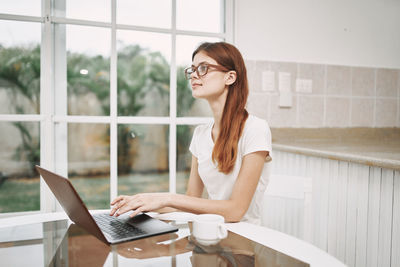 Young woman using phone while sitting on table