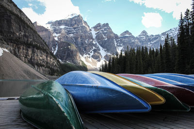 Upside down image of colorful boats on pier by lake against rocky mountains