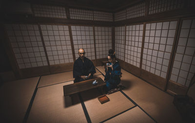 Side view of men sitting on floor against wall