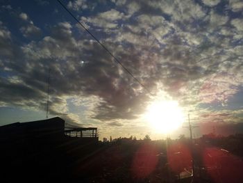 Silhouette of buildings against cloudy sky at sunset