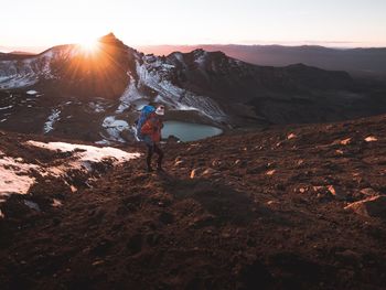 Man standing on rock against sky during sunset