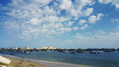 Boats moored at harbor against sky in city