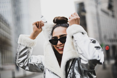 Portrait of cheerful woman wearing warm clothing in city