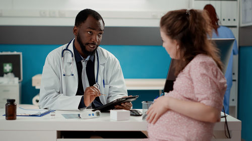 Doctor discussing with pregnant woman at clinic