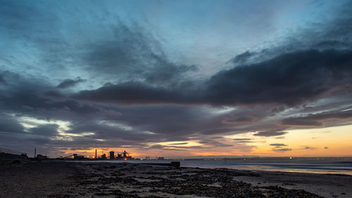 Scenic view of sea against dramatic sky during sunset