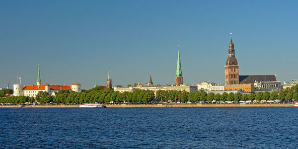 River by buildings against clear blue sky