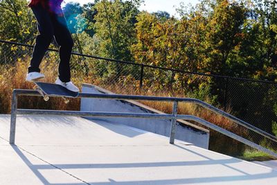 Low section of man standing by railing against trees