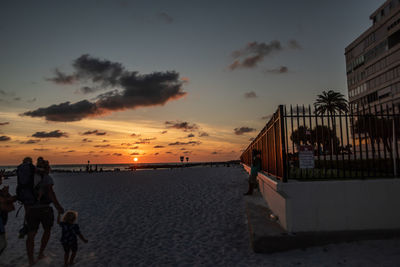 People on beach against sky during sunset