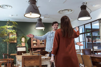 Male and female friends greeting each other at cafe