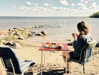 Side view of woman having breakfast at beach on sunny day